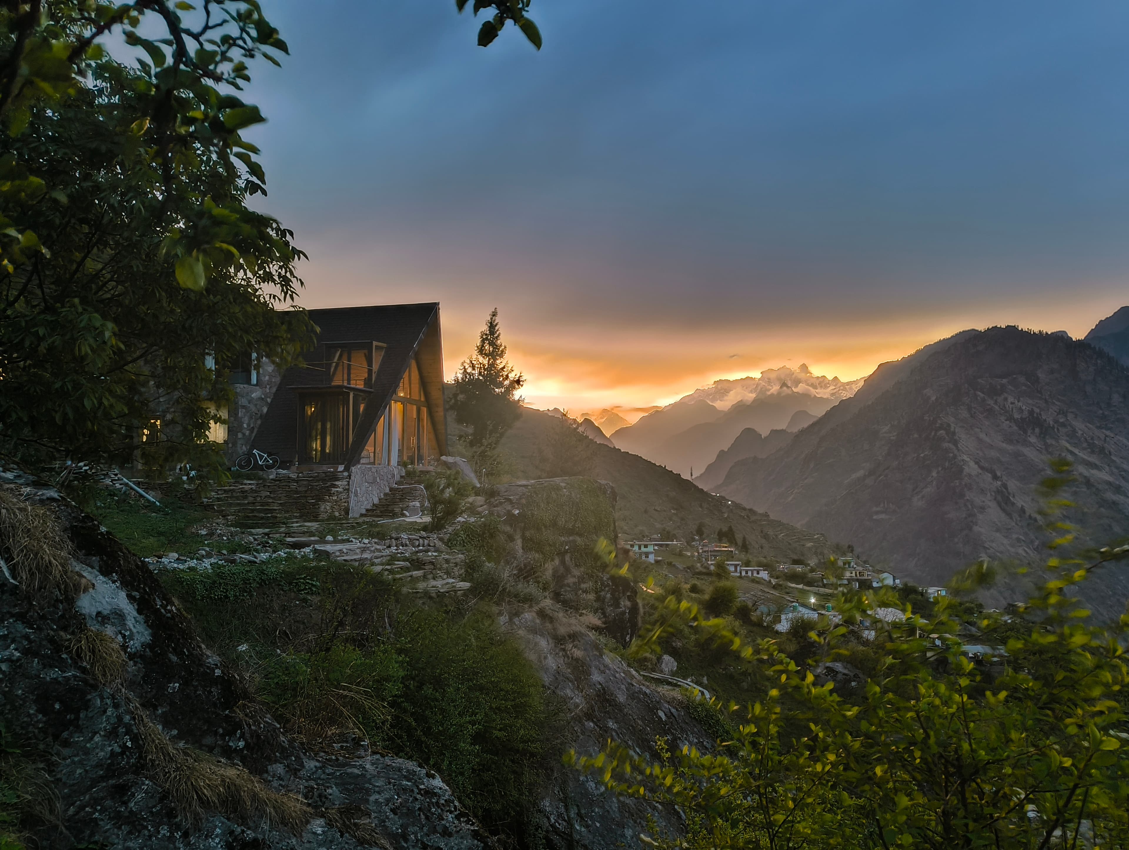 Vaadi homestay at sunset, A-frame cabin perched on a mountainside with Himalayan peaks in the background