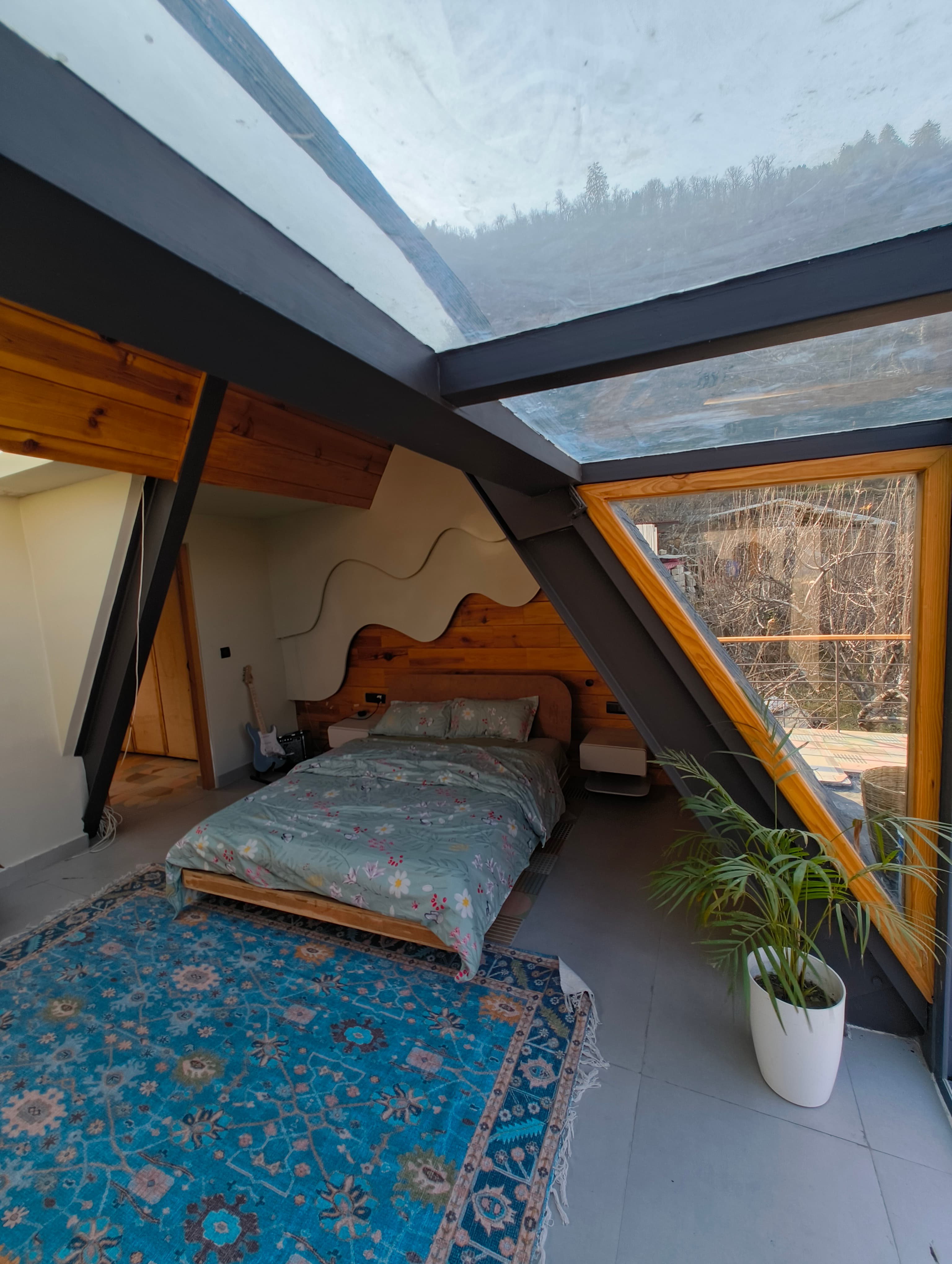Sky View room — bedroom with mountain-wave headboard, blue rug, and skylight