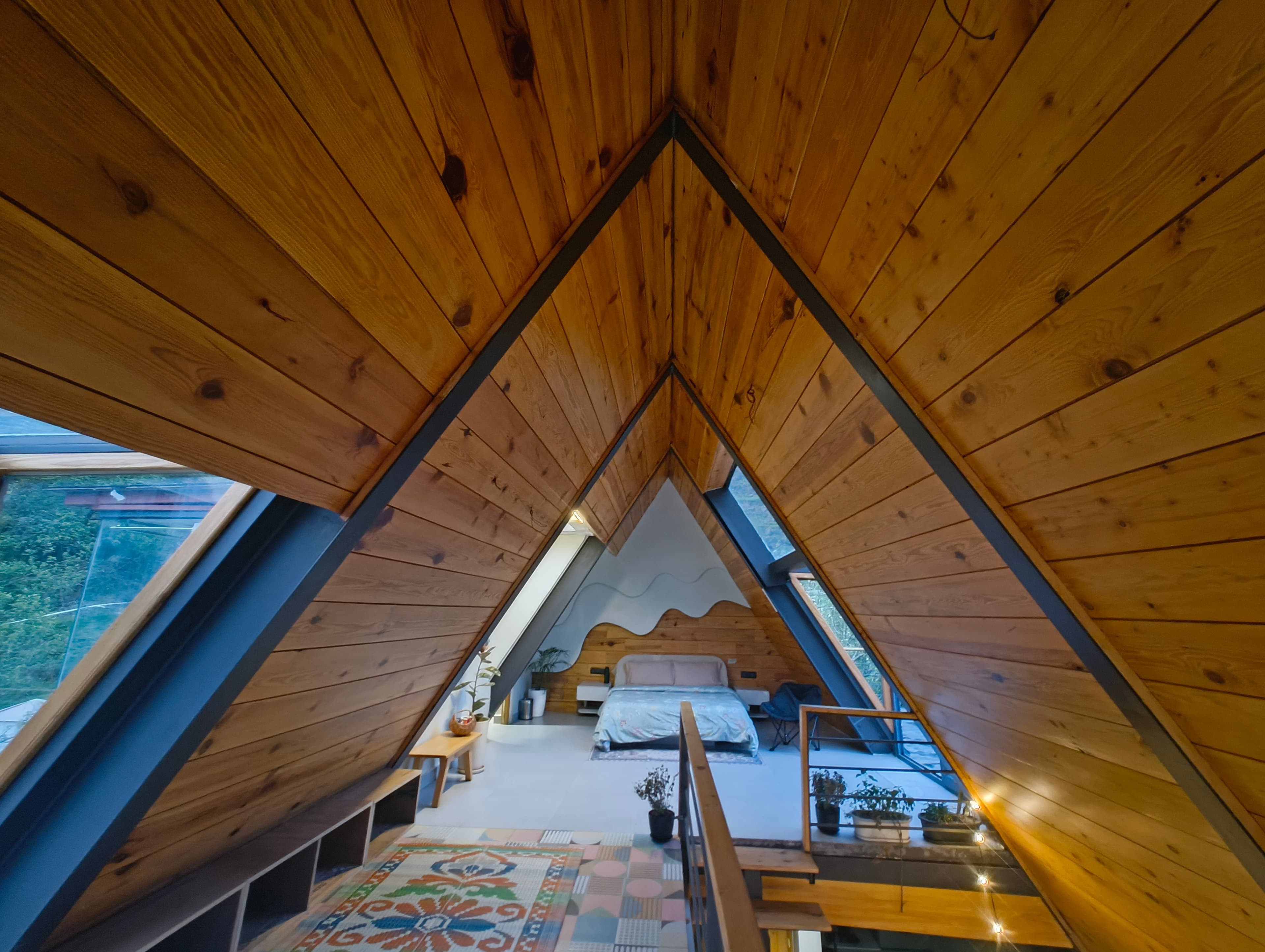 Sky View room — A-frame loft with warm wood ceiling and panoramic glass walls